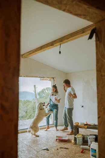 Photo of happy couple and their dog inside a home being renovated with renovations being paid for via refinancing their mortgage