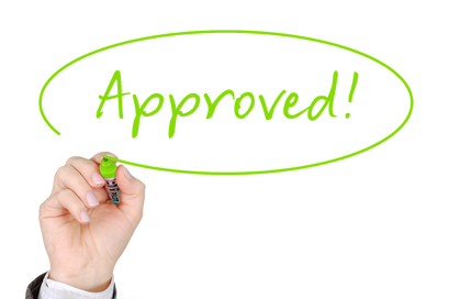Picture of a hand writing the word approved representing getting approved for a mortgage or home loan