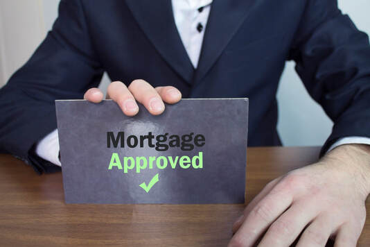 photo of a mortgage broker holding a sign that says mortgage approved